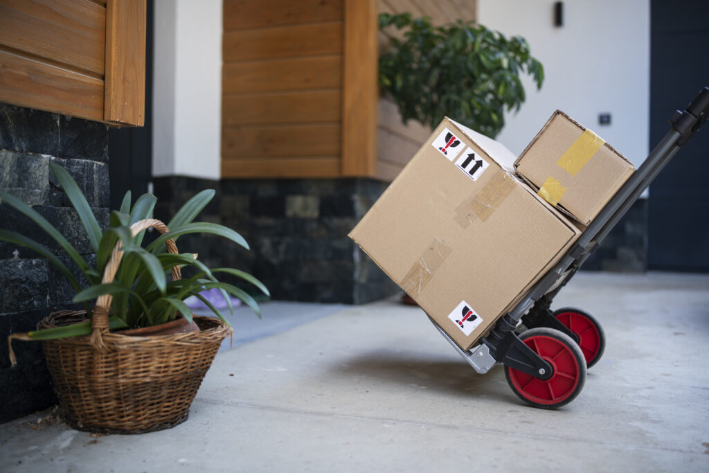 Close up of push cart full of delivery packages next to door.
