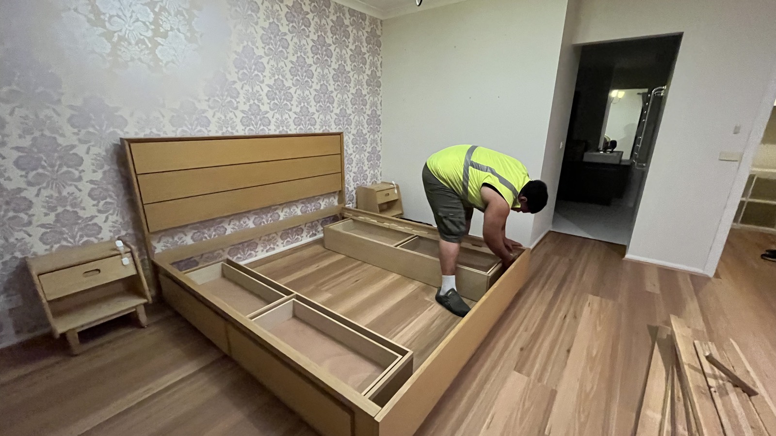 Host Movers removalist reassembling a timber bed frame in a customer’s new bedroom after the move