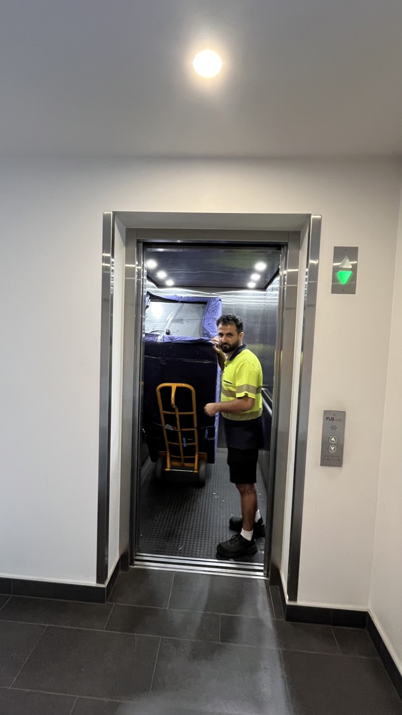 Host Movers removalist bringing a wrapped item into the lift on a trolley during a Melbourne apartment move