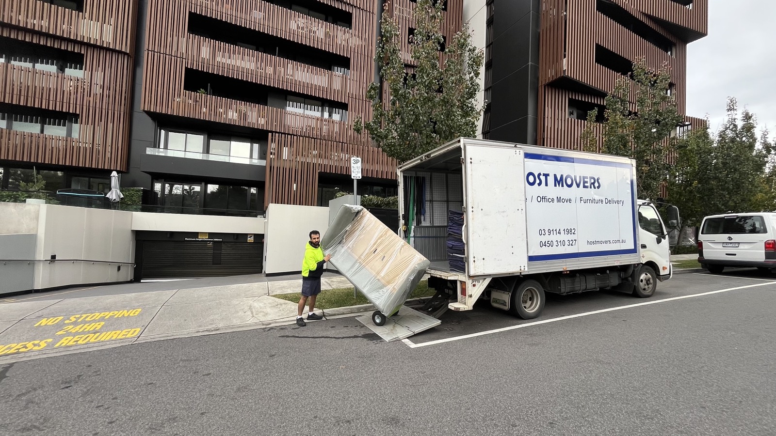 Host Movers removalist wheeling a blanket-wrapped item from the truck into a Melbourne apartment building
